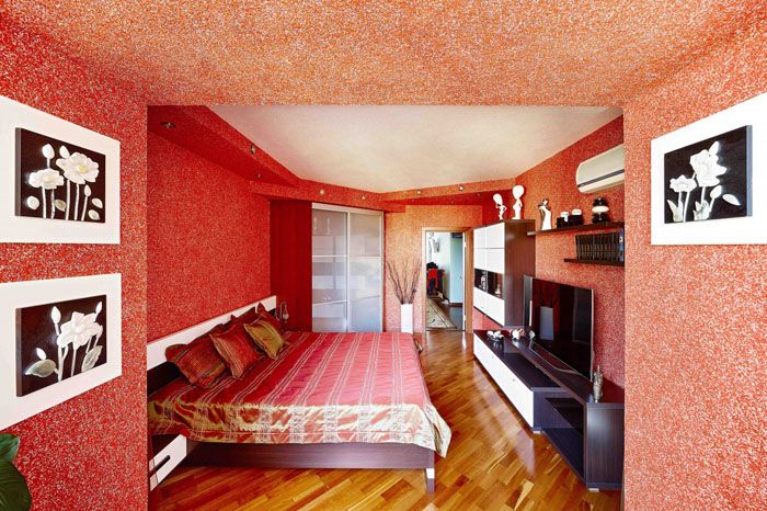 Красный тон стен кого-то раздражает, но в сочетании с тоном мебели и общего декора спальня выглядит милой и чуточку волнующей