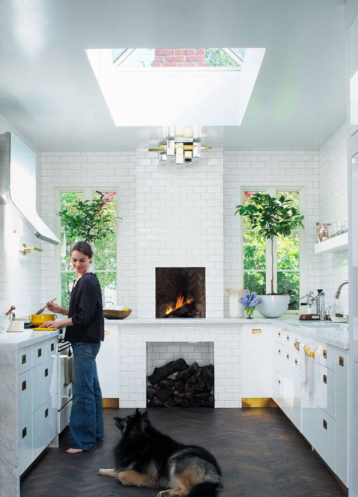 Белый интерьер кухни с камином и мансардным оном фото